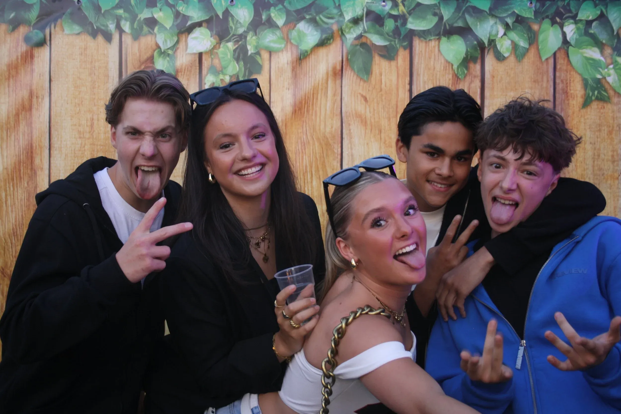 Een vriendengroep steekt lachend de tong uit voor de fotobooth tijdens de feestweek
