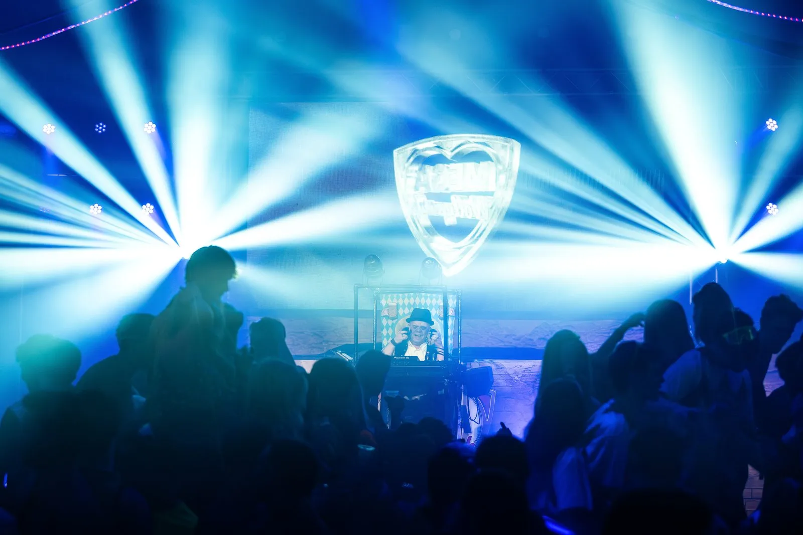 Blauwe lichtstralen boven een volle dansvloer tijdens een feest